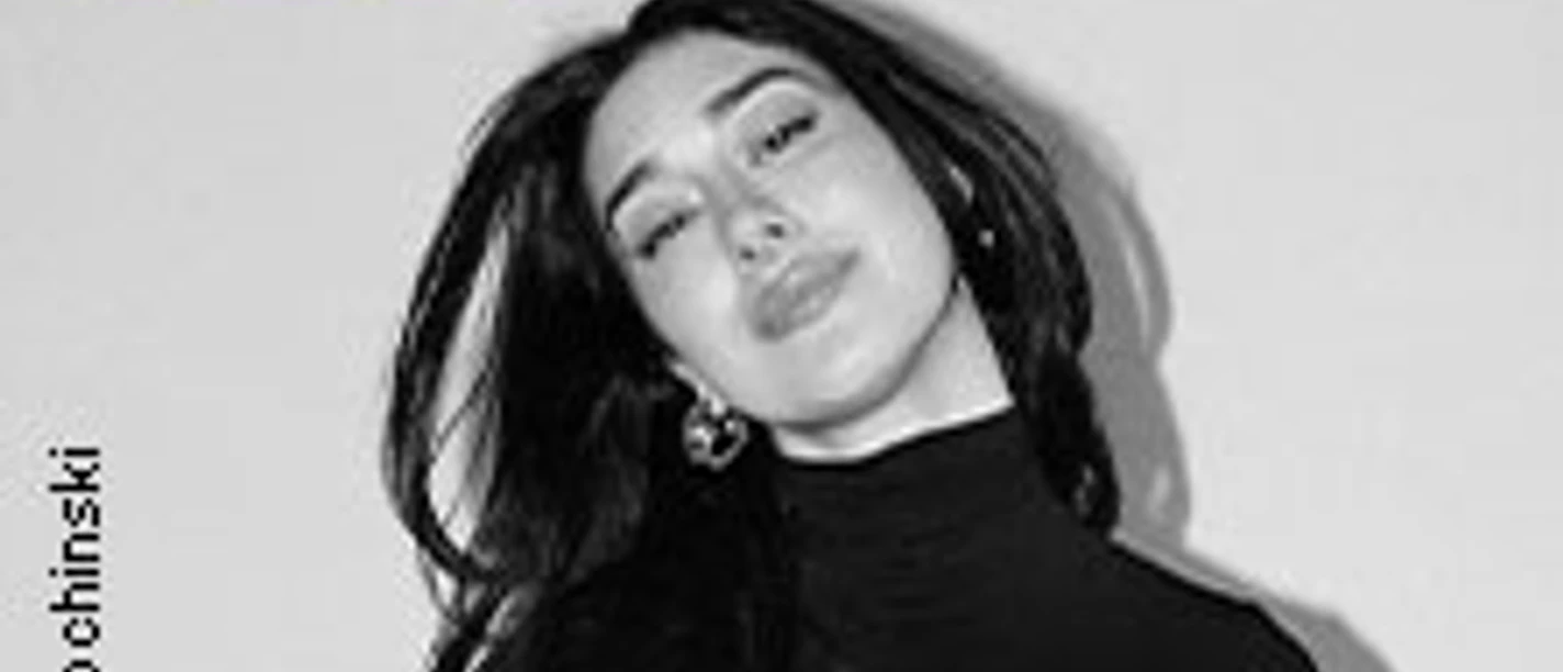 Schwarz-Weiß-Porträt von ELIF in elegantem Outfit mit geschlossenen Augen, Schrift darüber.