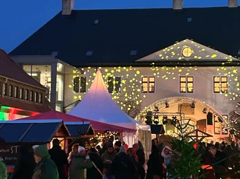 Schloss Benkhausen Winterliches Schlossvergnügen Menschen besuchen am Abend einen beleuchteten Weihnachtsmarkt vor Schloss Benkhausen.