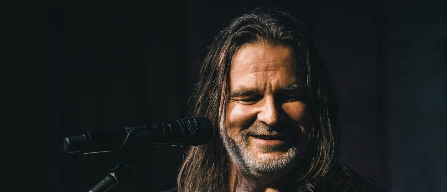 RAY WILSON c by Stefan Strassenburg Een muzikant met een gitaar zingt op het podium en lacht in de microfoon tijdens het optreden.