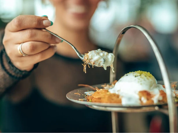 Gericht auf einem kreativ angerichteten Teller Eine lächelnde Person genießt ein vorzügliches Gericht auf einem kunstvoll gestalteten Teller.