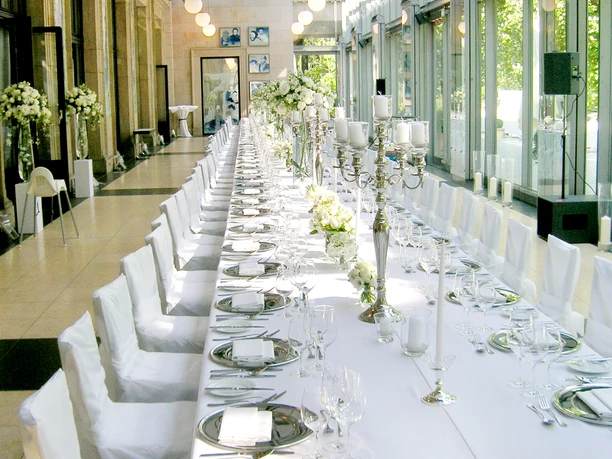 Kurhaus Wiesbaden - Wintergarten Lange, weiße Festtafel im Wintergarten.