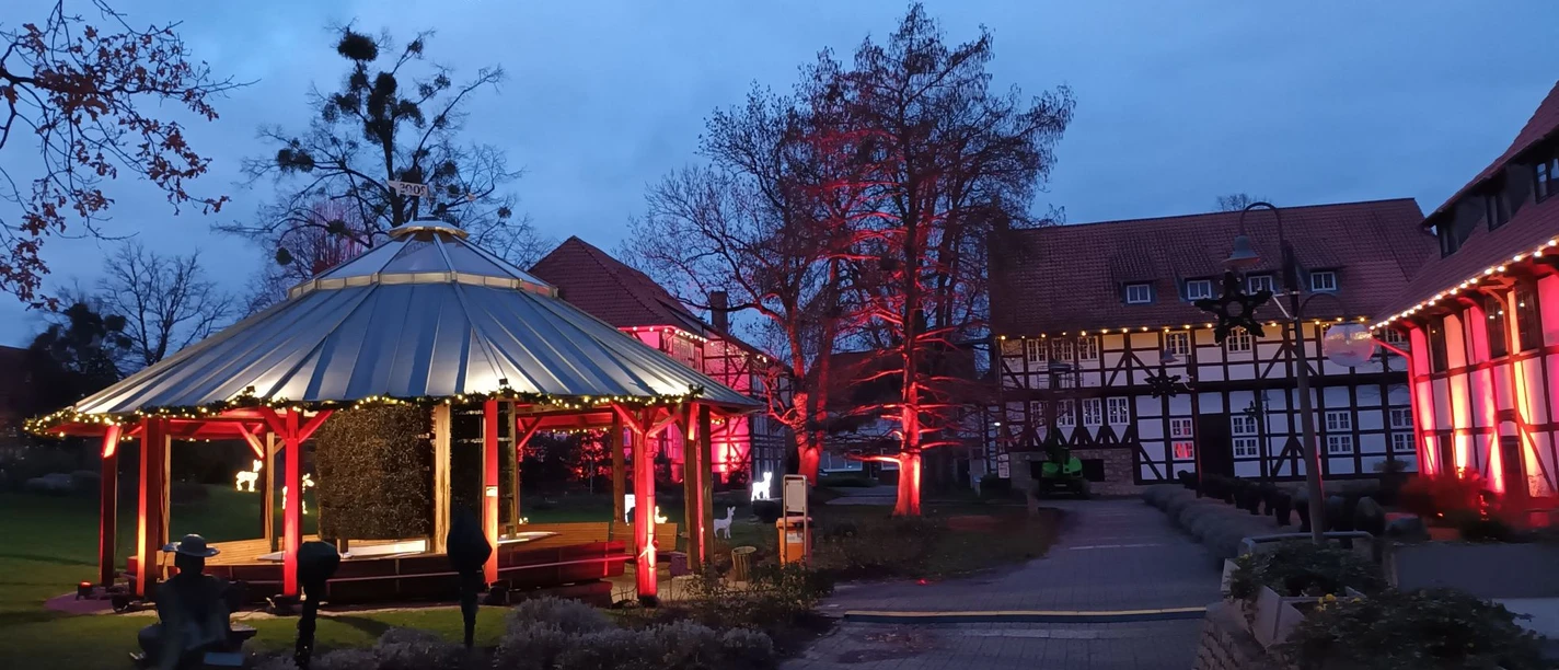 Rot beleuchteter Gradierpavillon im Rosengarten Salzgitter-Bad bei Abenddämmerung.