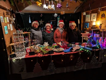 Weihnachtsmarkt Torhaus Markkleeberg - Weihnachten in der Region Leipzig Vier Personen in Weihnachtsmützen stehen hinter einem Verkaufsstand mit handgefertigten Artikeln.