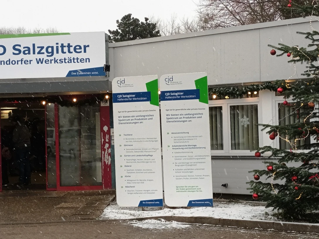 Adventsmarkt CJD_HD_16zu9.jpg Eingangsbereich der CJD Salzgitter Werkstätten mit beleuchtetem Weihnachtsbaum im Schneefall