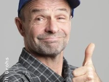 Mann mittleren Alters mit Schirmmütze und Daumen hoch, lächelnd im karierten Hemd.