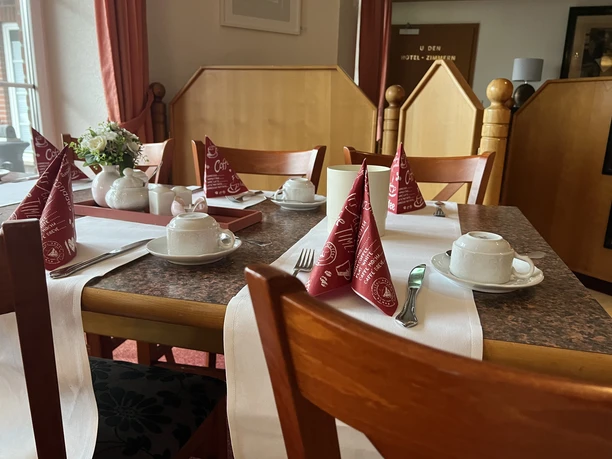 Frühstück im Grasberger Hof Gedeckter Frühstückstisch mit Porzellan, roten Servietten und Blumenschmuck im Hotelrestaurant.