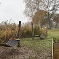 Rastplatz vor dem Naturparkhaus.JPG Holzpfosten mit Netzschaukeln auf einer Wiese vor herbstlicher Vegetation und Häusern im Hintergrund.