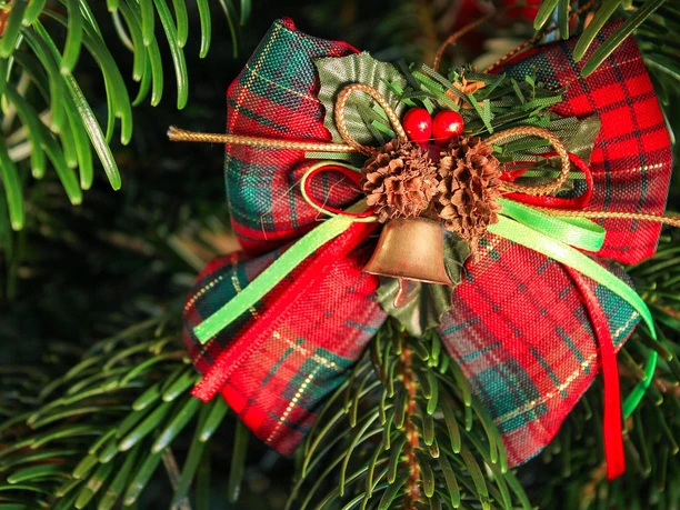 Weihnachtsschleife im Tannengrün Ein handgefertigter Weihnachtsanhänger aus Tannenzweigen mit rot-grüner Schleife und Glocke.