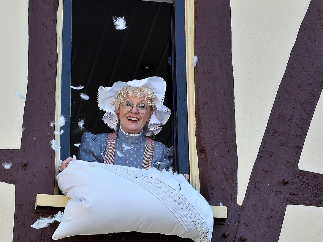 Frau Holle Eine Frau schüttelt ein Kissen aus dem Feder als Schnee fallen.
