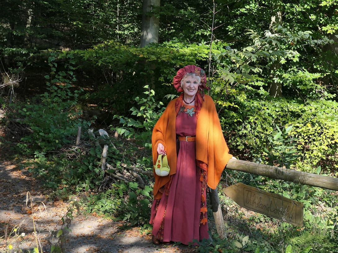 Hänsel und Gretel Eine Frau steht verkleidet als Märchenerzählerin im Wald.