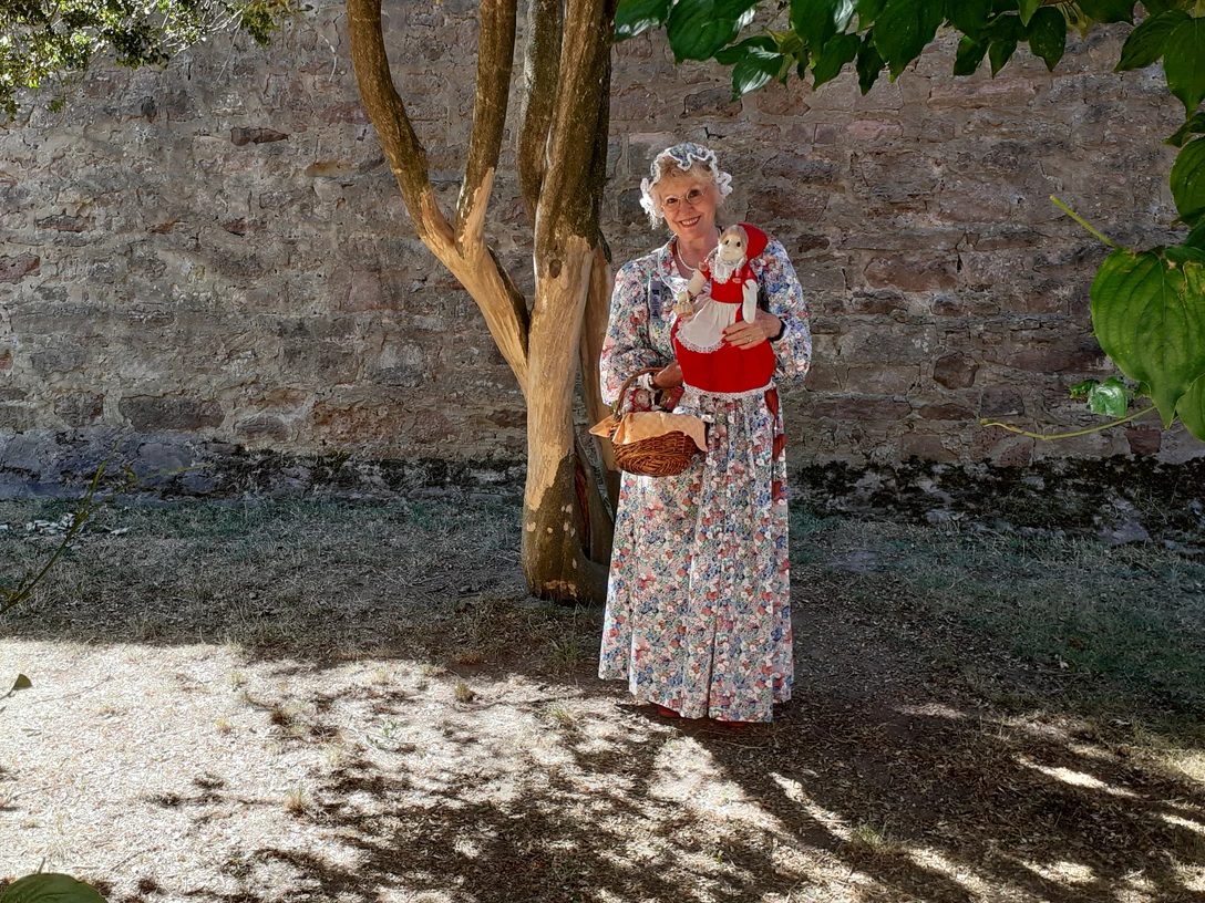 Rotkäppchen Eine Frau als Großmutter verkleidet hält eine Rotkäppchenpuppe im Arm.