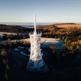 Blick auf die HEX Erlebniswelt von oben Moderner HEX Aussichtsturm in winterlicher Hügellandschaft mit Wald und weiten Ausblicken im Harz.