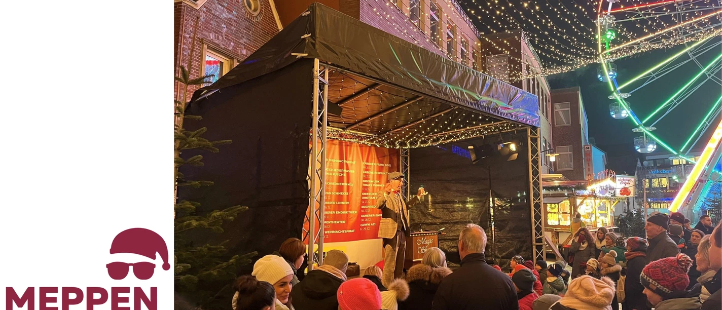 Kinderbühne Weihnachtsmarkt Meppen.png Bühne mit Zauberer auf dem Weihnachtsmarkt Meppen, umgeben von Kindern und Lichterglanz