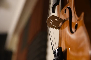 Cello Nahaufnahme eines Cellos mit Saiten und Steg, warme Lichtreflexe betonen den Holzglanz.