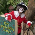 Gestiefelter Kater Märchen Eine Frau als Katze verkleidet kommt aus dem Buch "Der gestiefelte Kater" gestiegen.
