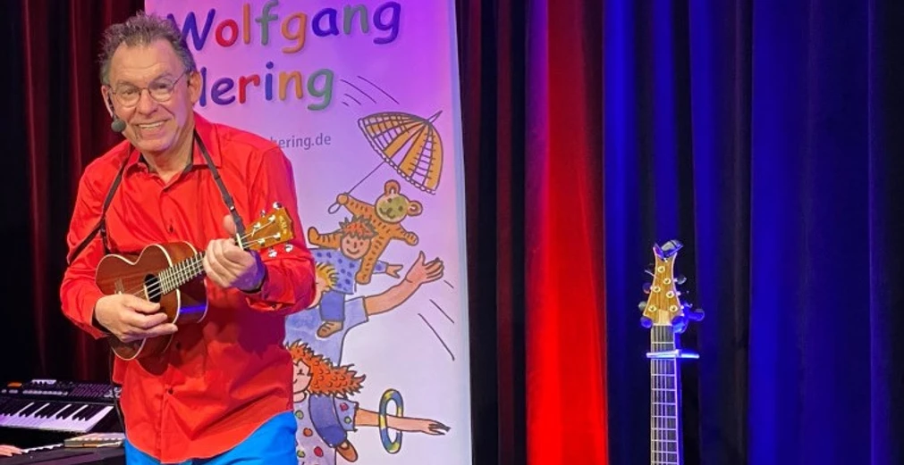 Wolfgang Hering Ein Mann spielt auf einer Ukulele und lächelt.