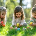 kind-ostereier-fruehling-wiese.jpg Drei kleine Mädchen sammeln bunte Ostereier im grünen Gras unter hellen Sonnenstrahlen.