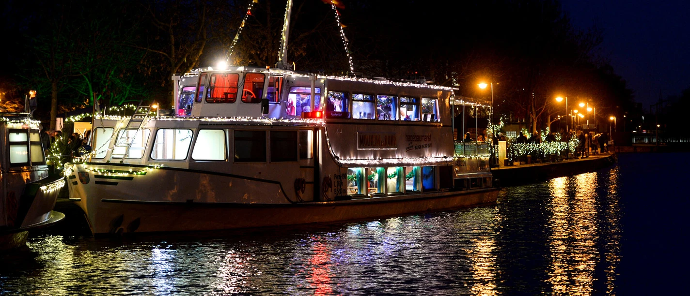Weiße Flotte, Mülheim an der Ruhr Ein festlich beleuchtetes Ausflugsschiff gleitet bei Nacht über ein ruhiges Gewässer.