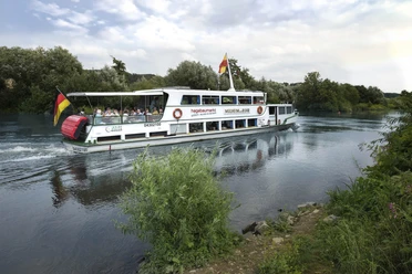 Weiße Flotte, Mülheim an der Ruhr Ein Ausflugsschiff fährt auf einem ruhigen Fluss, umgeben von grünen Bäumen.