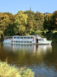 Weiße Flotte, Mülheim an der Ruhr Das Schiff "Heinrich Thöne" der Weißen Flotte fährt auf einem ruhigen Fluss durch grünen Wald.