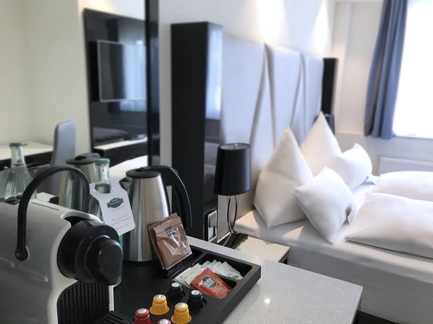 Mercure Hotel Kaiserhof Frankfurt City Center - Hotelzimmer Modernes Hotelzimmer mit Bett und Kaffeestation.