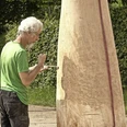 Holger Vanicek_Skulpturen-ReadyMades-Raumgreifungen (c) Museum Zinkhütter Hpf e.V..jpg Ein Künstler arbeitet konzentriert an einer großen Holzskulptur im Freien.