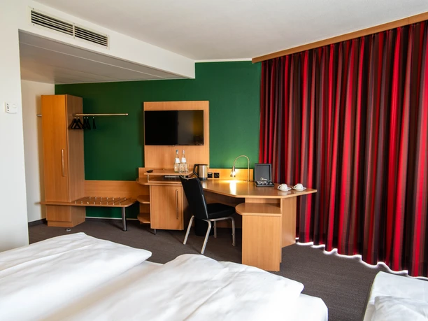 Best Western Mörfelden - Hotelzimmer Hotelzimmer mit grüner Wand und roten Vorhängen.