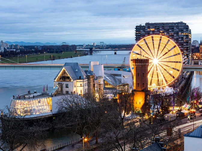 Kölner Hafenweihnachtsmarkt am Schokoladenmuseum Blick auf den hell erleuchteten Weihnachtsmarkt am Schokoladenmuseum Köln, mit dem Rhein im Hintergrund.View of the brightly lit Christmas market at the Cologne Chocolate Museum, with the Rhine in the background.