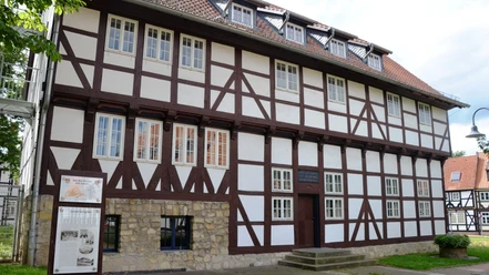 Kniestedter Gutshaus_HD_16zu9.JPG Historisches Fachwerkhaus mit dunklen Balken, weißer Fassade und massivem Steinsockel.