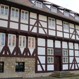 Kniestedter Gutshaus_HD_16zu9.JPG Historisches Fachwerkhaus mit dunklen Balken, weißer Fassade und massivem Steinsockel.