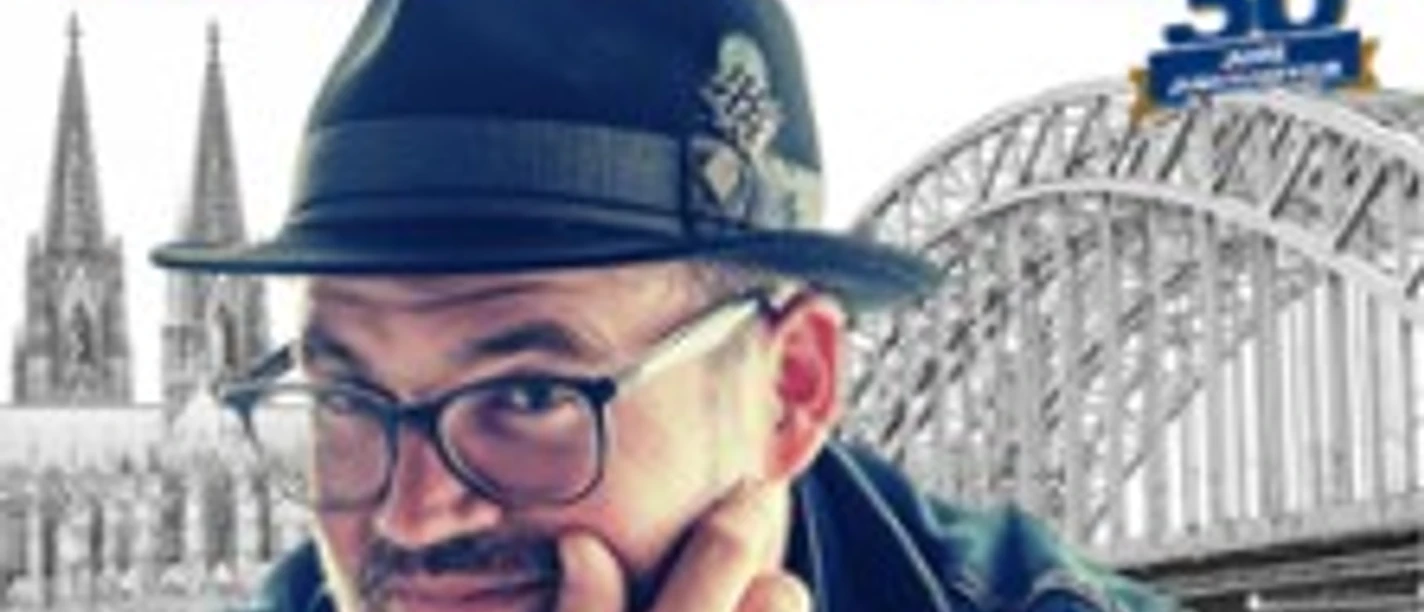 Björn Heuser vor der Kölner Dom-Silhouette und Hohenzollernbrücke.