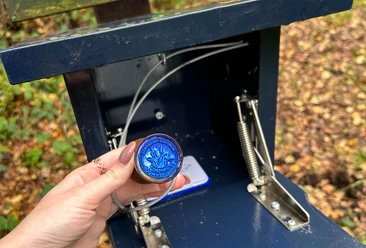 Stempel-Nordsee-Reisepass-Torfspitt-Kayhausen-Bad-Zwischenahn.jpg Hand hält blauen Nordsee-Reisepass-Stempel vom Torfspitt Kayhausen vor geöffneter Stempelbox.
