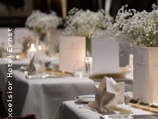 Elegantes Restaurant mit gedeckten Tischen, weiße Tischdecken, Blumenarrangements.