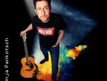 Ein Musiker mit Brille hält eine Gitarre und trägt ein schwarzes "Melvis"-Shirt.