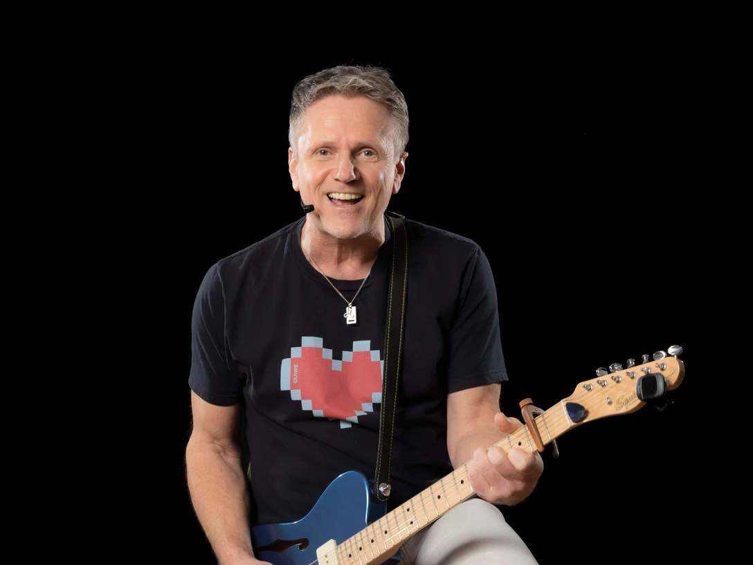 Martin Pfeiffer Kinderliedersaenger Martin Pfeiffer mit E-Gitarre singt Kinderlieder vor schwarzem HintergrundMartin Pfeiffer playing electric guitar and singing kids' songs onstage