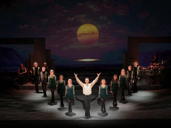 Riverdance 30 – Die neue Generation Tänzerinnen und Tänzer auf einer Bühne, Sonnenuntergang mit magischer Atmosphäre im Hintergrund.Dancers on a stage, sunset with a magical atmosphere in the background.