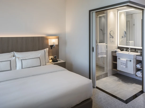 Melia Frankfurt City - Hotelzimmer Hotelzimmer mit Bett und offenem Bad.