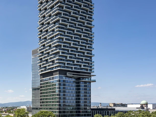 Melia Frankfurt City - Modernes Hochhaus Modernes Hochhaus über Baumwipfeln.