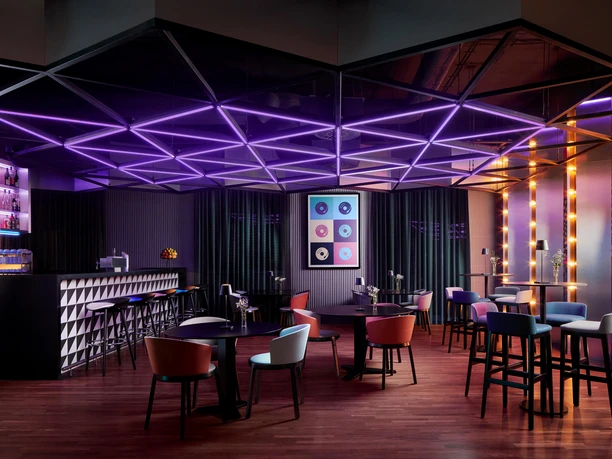 AVANI Frankfurt City - Bar Stylische Bar mit lila Neon-Decke und Lounge-Möbeln.