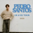 Pedro Santos steht lässig vor einer Wand mit Tourdaten für UK und EU im Jahr 2026.