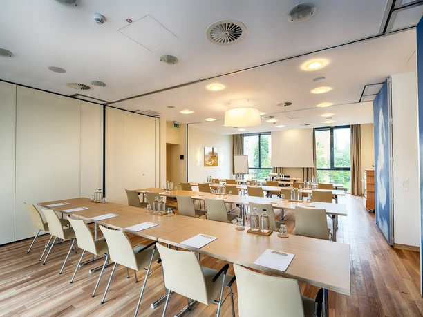 Best Western Plus Welcome Hotel Frankfurt - Tagungsraum Heller Tagungsraum mit Tischreihen und Wolken-Wand.