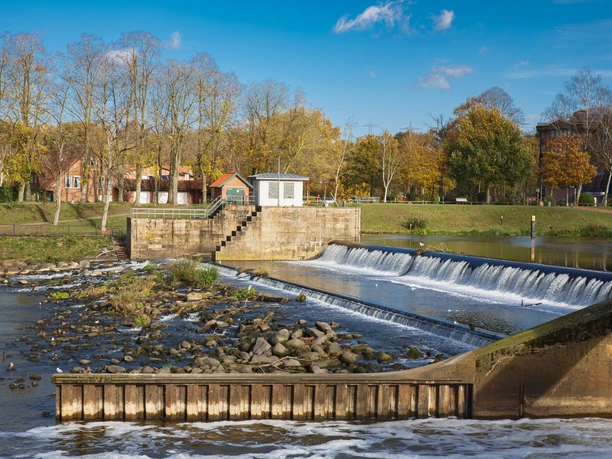 Wasserfall Hanekenfähr Wasserfall Hanekenfähr mit fließendem Wasser an einer Staustufe, umgeben von herbstlichen Bäumen.