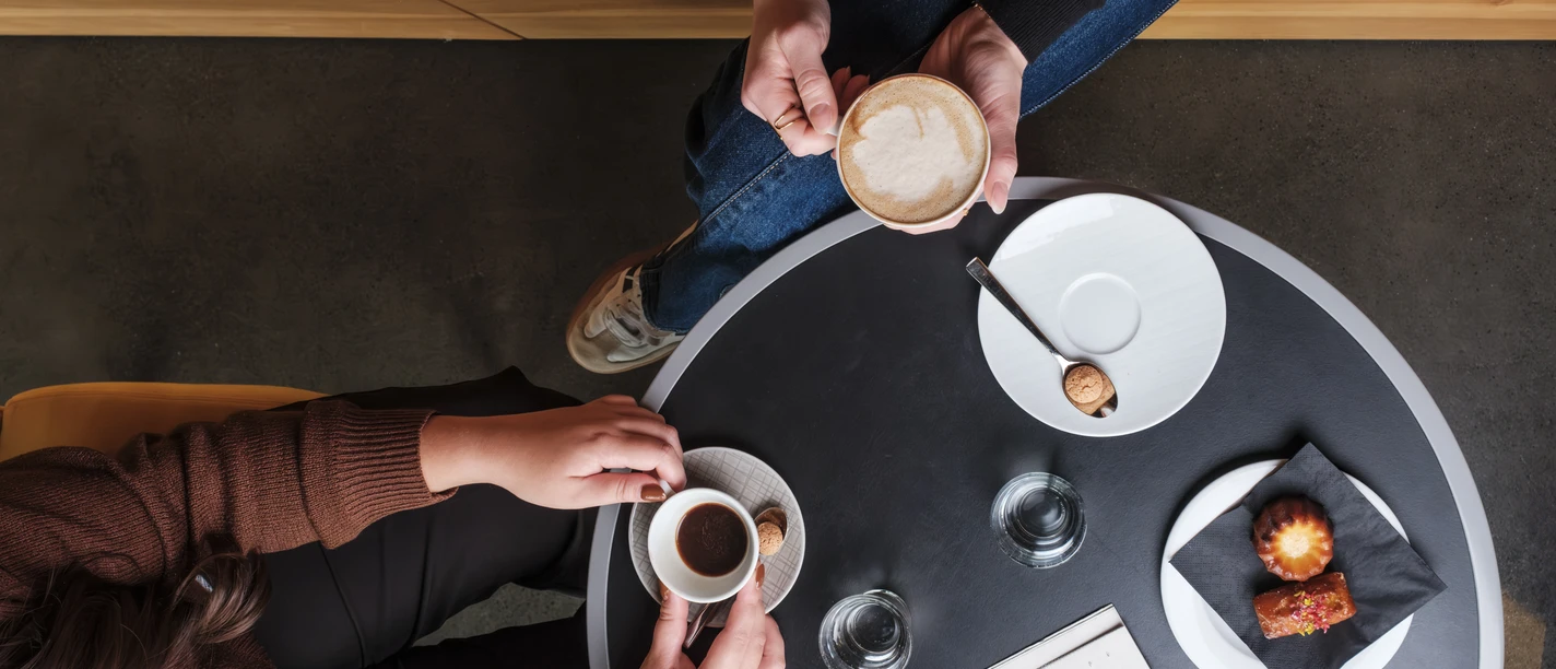 Coffee Card_20251009_111336__DSF4729.jpg Ein Tisch im Café aus der Vogelperspektive mit Kaffeetassen und Gebäck bestückt.