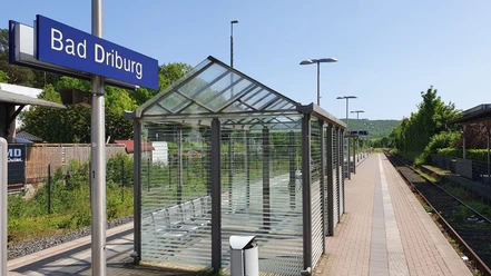 Bad-Driburg-Bahnhof Gleisanlage am Bahnhof Bad Driburg mit überdachtem Wartebereich und Blick auf grüne Hügel.