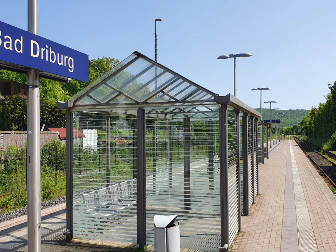 Bad-Driburg-Bahnhof Gleisanlage am Bahnhof Bad Driburg mit überdachtem Wartebereich und Blick auf grüne Hügel.