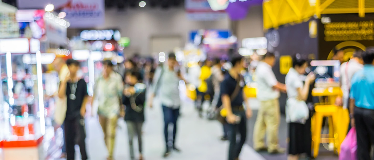Otterndorfer Gewerbemesse Menschen gehen durch eine Messehalle mit hell beleuchteten Ständen und modernen Ausstellungsflächen.