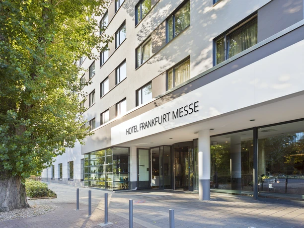 Frankfurt Messe Affiliated by Meliá - Hotelfassade Helle Hotelfassade mit Eingangsbereich und Baum.