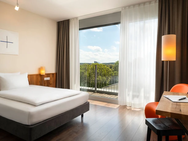 mainhausStadthotelFrankfurt - Hotel rooms Bright hotel room with balcony and wooden floor.