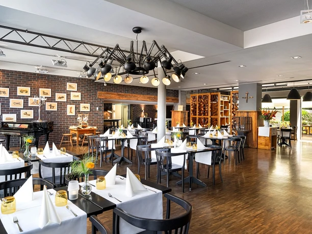 mainhausStadthotelFrankfurt - Restaurant Restaurant mit gedeckten Tischen und Backsteinwand.