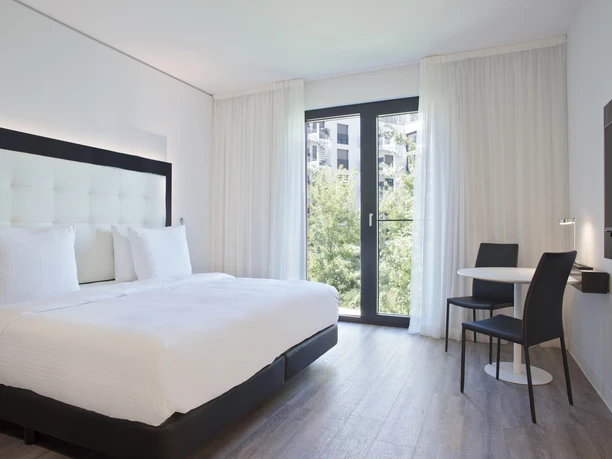 INNSiDE Frankfurt Ostend - Hotel rooms Bright hotel room with white bed and black seating area.